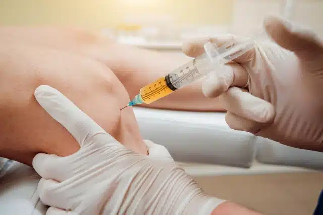 Chiropractor doing some Hyaluronic Acid knee Injection to the patient