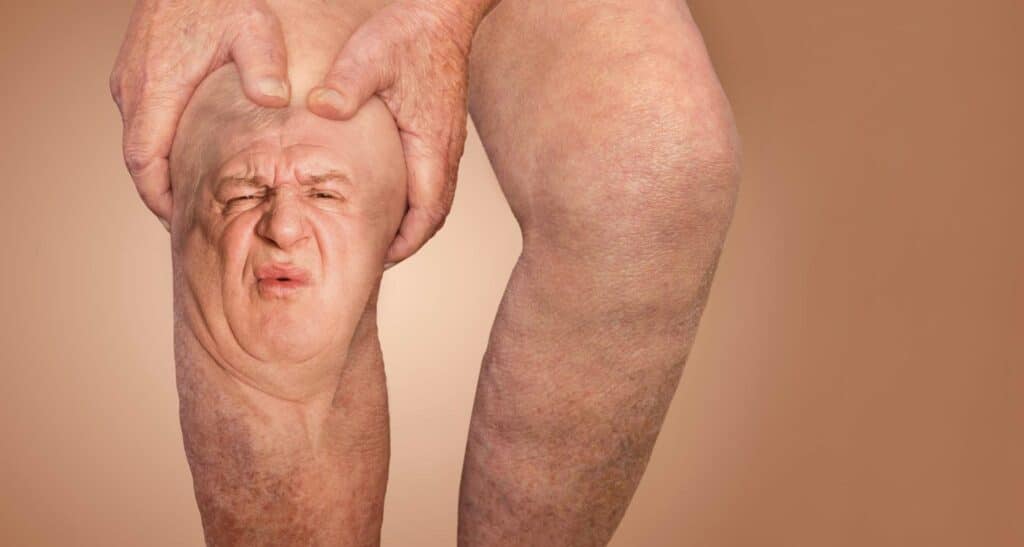 man's face in pain on a knee - arthritis concept