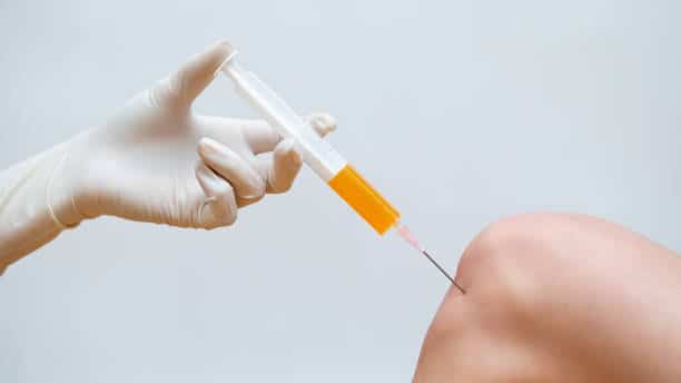 Doctor injecting a prp treatment on a patients knee