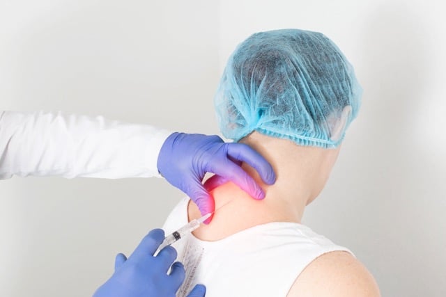 Chiropractor is doing the trigger point injection to the patient