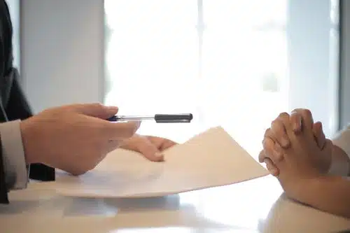 hand of a office worker handing a person a pen and care plan on a paper