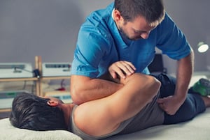 male chiropractor adjusting a male patient's lower back
