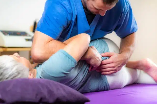 male chiropractor adjusting a female elder's lower back