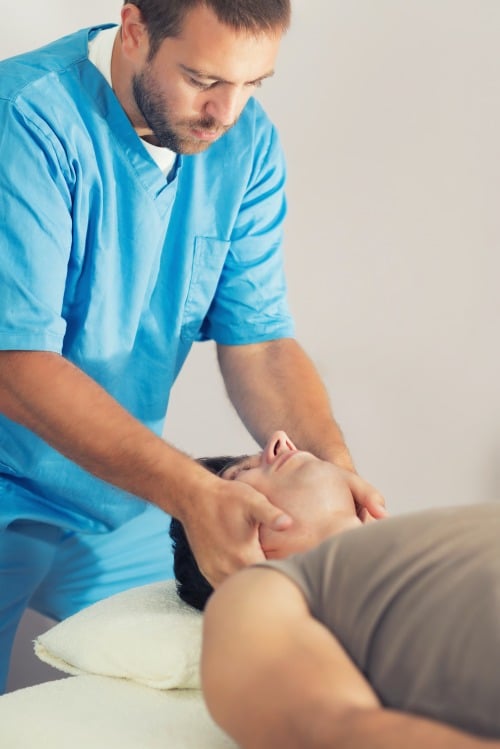 chiropractor adjusting a male patient's neck