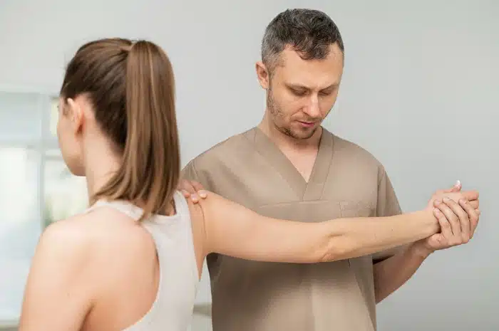 Woman receiving soft tissue therapy for shoulder pain at a chiropractic clinic