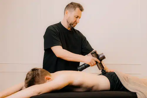 chiropractor using massage gun to treat sciatica for manual massage therapy and spinal chiropractic adjustment | what is sciatica